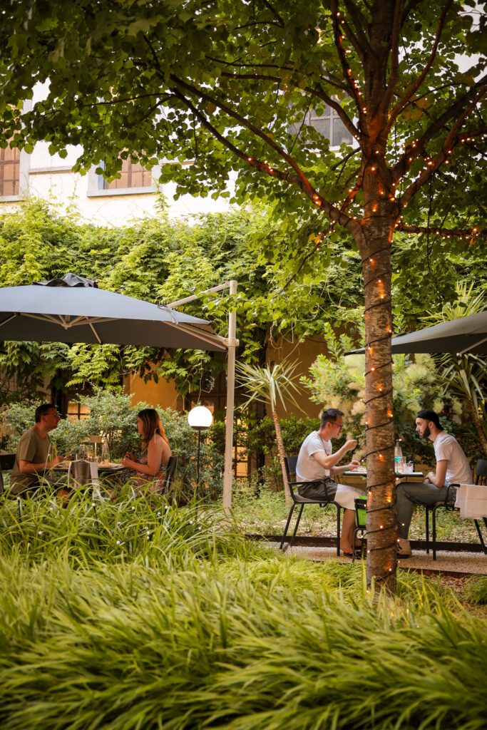 Clients déjeunant dans la cour jardin ombragée du Grand Hôtel-Dieu de Lyon.
