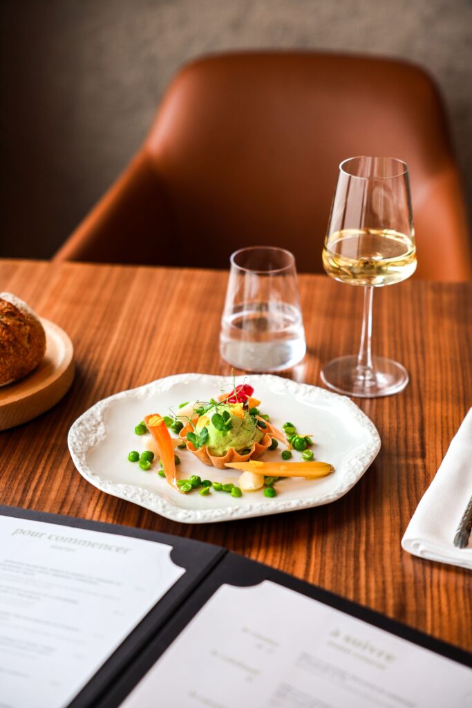 Entrée gastronomique : tartelette de légumes printaniers, petits pois et carottes avec verre de vin blanc, restaurant Epona.