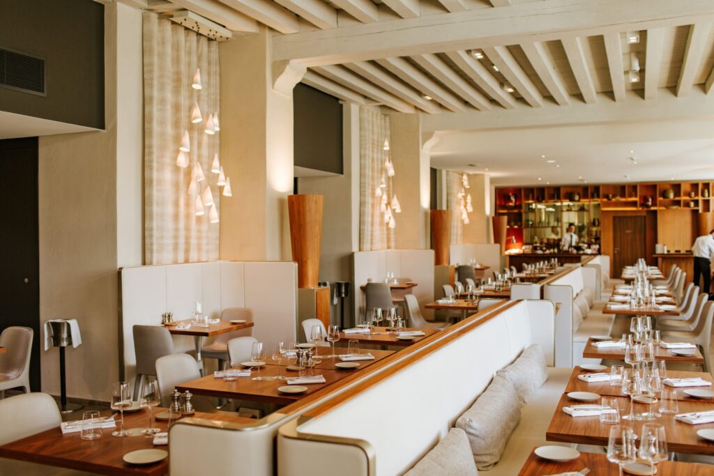 Intérieur design du restaurant Epona à Lyon avec tables en bois, banquettes blanches et luminaires contemporains.